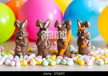Easter. Four chocolate bunnies, sugar eggs. Multicolored balloons background Stock Photo