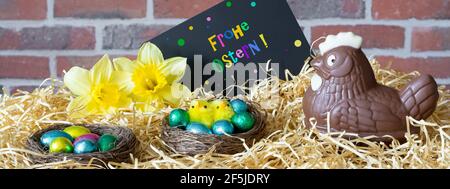 Easter, decoration on the straw. Chocolate Easter egg hen, and slate with german inscription "Happy Easter". "Frohe Ostern" Stock Photo