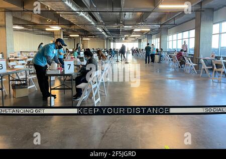 Frisco TX, USA - March 26, 2021: Indoor view of people wearing mask and filling up the COVID 19 vaccination form Stock Photo