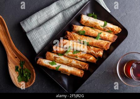 Traditional Turkish sigara boregi, a phyllo dough roll with cheese or ground meat stuffing. Deep fried rolls are served on a tray with parsley leaves Stock Photo