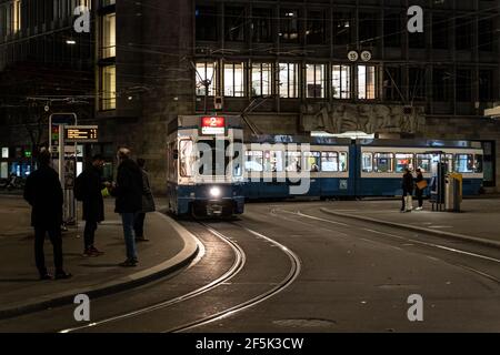 Zurich, Switzerland - October 27 2020: People wait for a tram at the Parade Platz stop in the heart of the business district of Zurich at night. Stock Photo