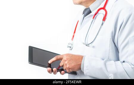 Medium shot of a doctor in a gown and tie whose face is not recognized with a stethoscope and a tablet on a white background. Medicine and technology Stock Photo