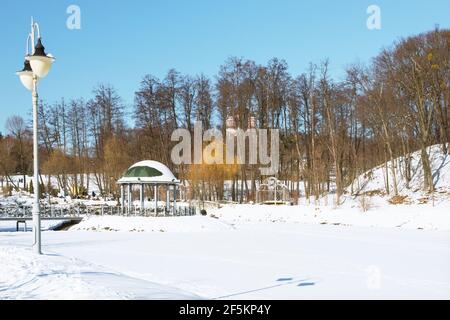 A fragment of the Feofania winter park in Kiev, a delightful view of the snow-covered lake and a beautiful gazebo. Stock Photo