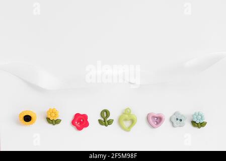 Sewing accessories on a white background. Sewing threads, pins, fabric, buttons. Top view, flat lay. Spring color Stock Photo
