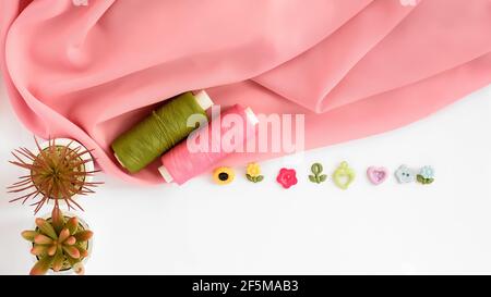Sewing accessories and fabric on a white background. Sewing threads, pins, fabric, buttons. Top view, flat lay. Spring color Stock Photo