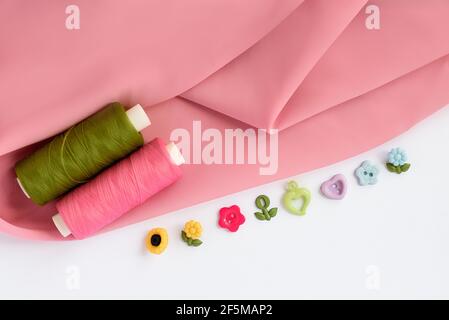 Sewing accessories and fabric on a white background. Sewing threads, pins, fabric, buttons. Top view, flat lay. Spring color Stock Photo