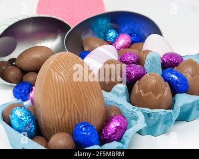 Lots of chocolate Easter eggs of different sizes in an egg carton and in egg-shaped containers Stock Photo