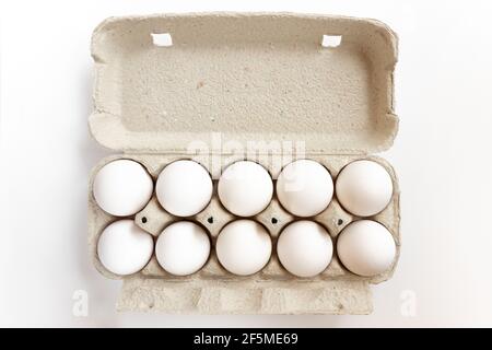 White chicken eggs in box. Cardboard egg box with chicken eggs on white background. Stock Photo