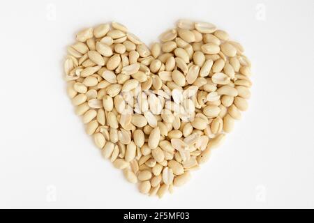 Salted peeled peanuts in a heart shape isolated on white background. Flat lay. From above. Stock Photo