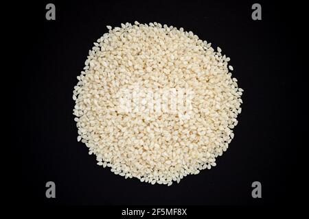 White sesame seeds heap isolated on black background. Top view. Stock Photo
