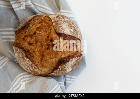 Freshly baked bread lying on linen towel, isolated on white background. Stock Photo