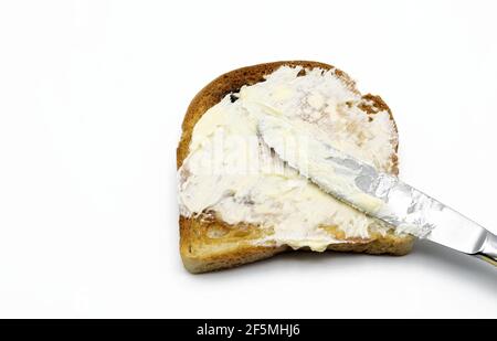 Spreading butter with a knife on toast isolated on white background Stock Photo