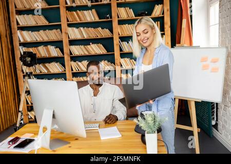 Successful multiracial business partners working on new project together in modern office, smiling. Happy stylish colleagues searching ideas for Stock Photo