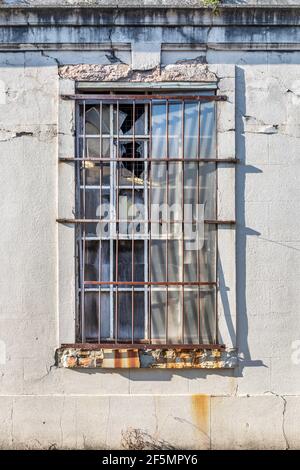 An old window with rusty bars set in a rough wall Stock Photo