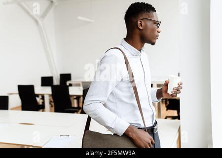 Afro american serious man in eyeglasses drinking coffee in office Stock Photo