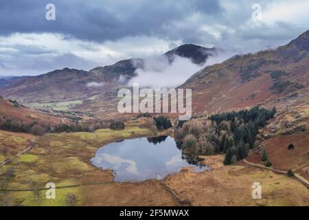 Epic aerial drone landscape image of Blea and valley in Winter with low level clouds and mist swirling around Stock Photo