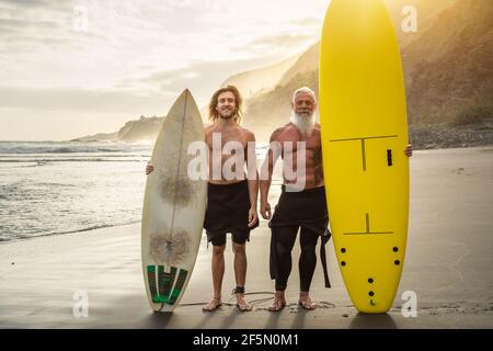 Happy friends with different age surfing together - Sporty people having fun during vacation surf day - Extreme sport lifestyle concept Stock Photo