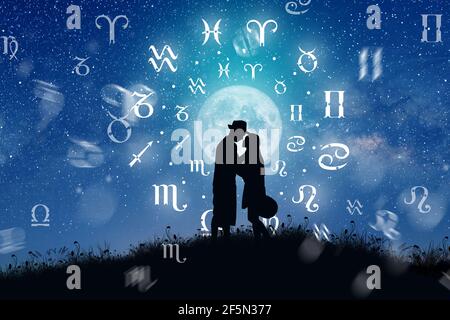 Astrological zodiac signs inside of horoscope circle. Couple singing and dancing over the zodiac wheel and milky way background. Stock Photo