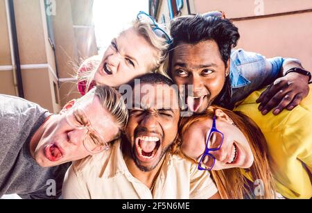 Multiracial millenial people taking selfie sticking out tongue with happy faces - Funny life style concept against racism Stock Photo