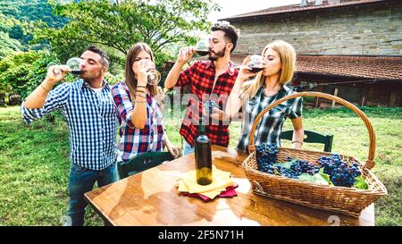 Happy friends having fun drinking at winery vineyard - Friendship concept with young people enjoying harvest together at farmhouse - Red wine tasting Stock Photo