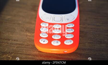Old nokia 3310 keypad phone isolated on wooden table background. Old Classic mobile cell phone with small screen. Nokia branded company in India. Stock Photo