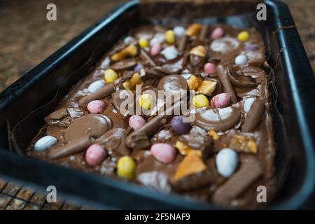 Home baking Easter concept. Brownie with chocolate bars, mini easter eggs and biscuits baked in. Chocolate feast home baked treat Stock Photo