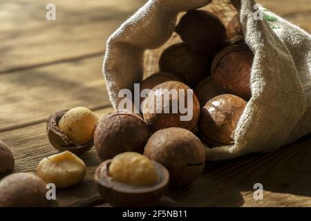 Macadamia nuts on wooden background in linen bag close up. Toned. Shallow depth of field Stock Photo