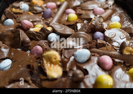 Home baking Easter concept. Brownie with chocolate bars, mini easter eggs and biscuits baked in. Chocolate feast home baked treat Stock Photo