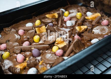 Home baking Easter concept. Brownie with chocolate bars, mini easter eggs and biscuits baked in. Chocolate feast home baked treat Stock Photo