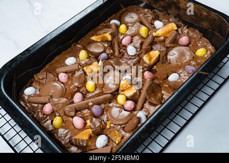 Home baking Easter concept. Brownie with chocolate bars, mini easter eggs and biscuits baked in. Chocolate feast home baked treat Stock Photo