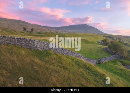 Vibrant, colourful sunrise or sunset sky over the beautiful countryside landscape of limestone pavement old stone walls at Southerscales in the Yorksh Stock Photo