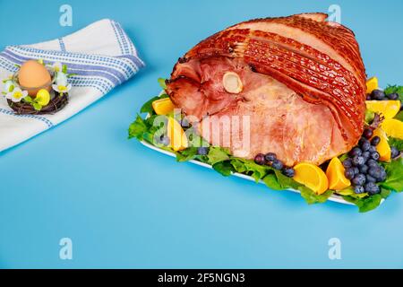 Spiral sliced and glazed ham on blue table. Stock Photo