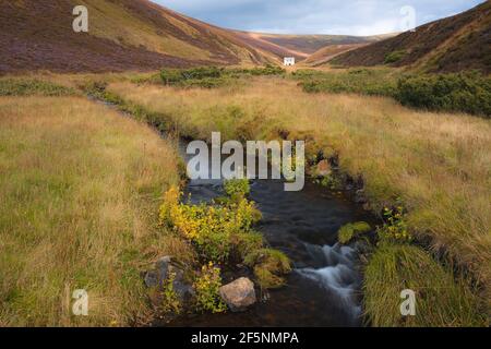 An old abandoned mining site, Lecht Mine and stream in the rolling hills countryside landsacpe of Cairngorms National Park, in the Scottish Highlands Stock Photo