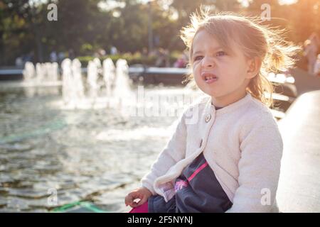 Evil expression face. Portrait of little angry toddler girl she grimaces and shows a grin Stock Photo