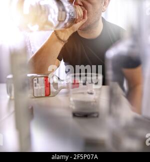 drunk man drinking vodka from a bottle Stock Photo