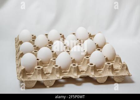close up of carton box with distanced white eggs on white background. concept of quarantine rules Stock Photo
