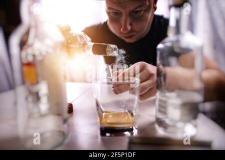 man with an alcohol problem drinks alcohol alone in a den Stock Photo
