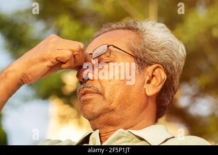 Head shot of worried senior old man rubbing his eyes - conept of healthcare, medical and stressed out elderly people Stock Photo