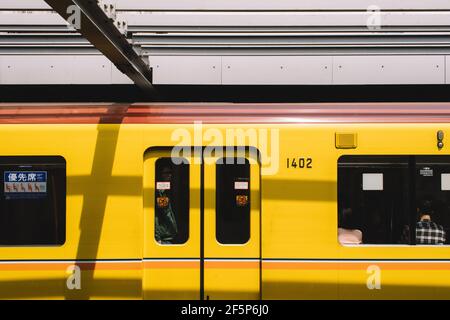 Tokyo, Japan - Tokyo metropolitan train stopped at Shibuya Station. Passengers in shadow. Stock Photo