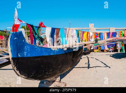 Traditional outrigger fishermen pirogue moored on Anakao coast with colorful pareo in the background, Indian Ocean, Madagascar Stock Photo