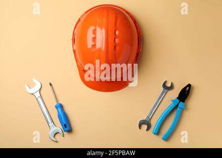 Hard hat and tools on beige background Stock Photo
