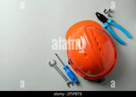 Hard hat and working tools on light gray background Stock Photo