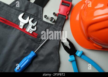 Overalls, hard hat and tools on light gray background Stock Photo