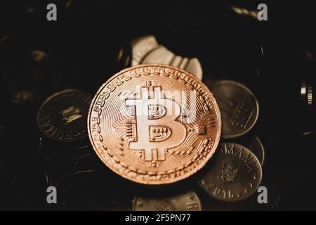 Shallow depth of field (selective focus) image with a Bitcoin metal coin on top of other metal coins (Romanian RON) - cryptocurrency concept. Stock Photo