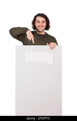 Positively surprised man pointing index finger to blank announcement banner, looking amazed to camera. Contented guy and empty sheet, copy space for p Stock Photo