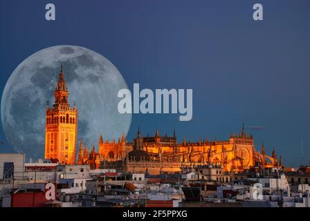 A full moon behind the illuminated cathedral in Seville, Spain Stock Photo