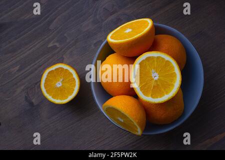 Fresh oranges in a light blue bowl on a dark wood background Stock Photo