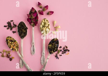 Tea composition.Different varieties of tea in the silver spoons on the pink background.Top view.Copy space. Stock Photo