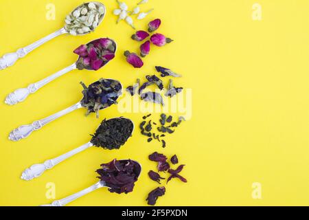 Tea composition.Different varieties of tea in the silver spoons on the yelllow background. Top view. Copy space. Stock Photo