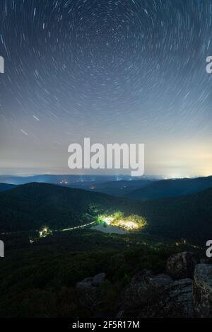 Light trails atop Sharp Top Mountain of Peaks of Otter looking down at the Peaks of Otter Lodge and Abbott Lake. Stock Photo